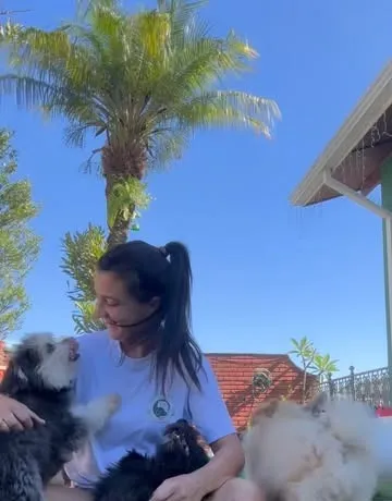 Dra. Nathalie sentada na grama com três cães